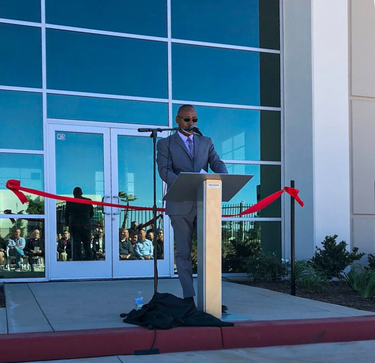 Greg behind a podium delivering a speech on the opening of a project.